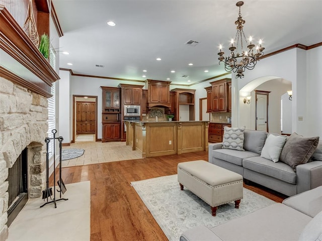 living room with a fireplace, a chandelier, light hardwood / wood-style flooring, and crown molding