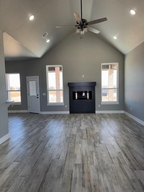 unfurnished living room with ceiling fan, a wealth of natural light, and wood-type flooring