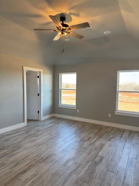 empty room with light wood-type flooring, ceiling fan, and lofted ceiling