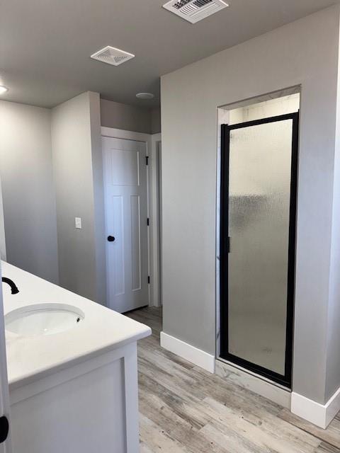 bathroom with hardwood / wood-style flooring, vanity, and a shower with door