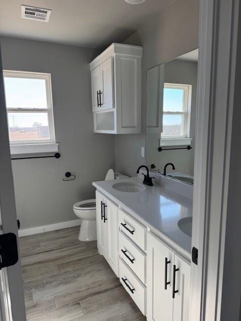 bathroom featuring vanity, toilet, plenty of natural light, and wood-type flooring