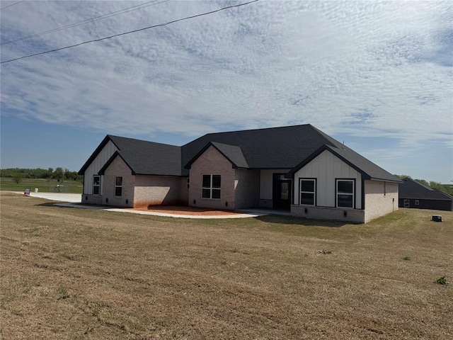 view of front of property featuring board and batten siding, a front lawn, and brick siding