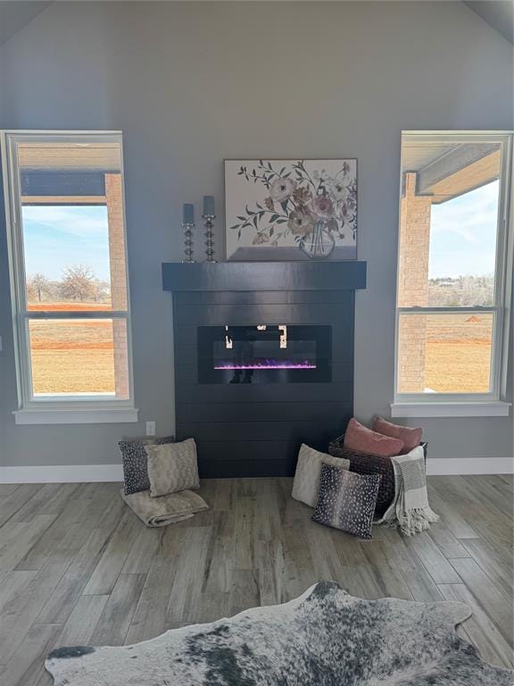 interior space featuring baseboards, a glass covered fireplace, and wood finished floors