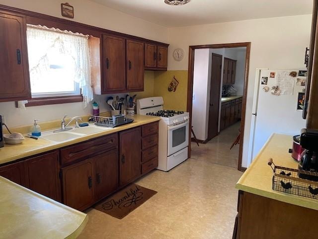 kitchen featuring dark brown cabinetry, white appliances, and sink