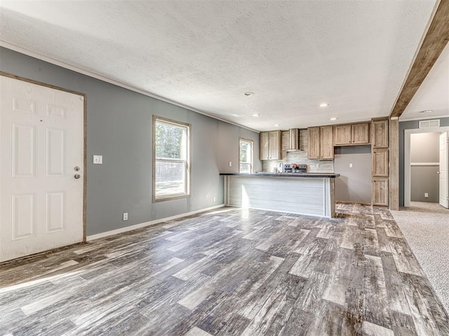 unfurnished living room with beamed ceiling, a textured ceiling, and light hardwood / wood-style floors