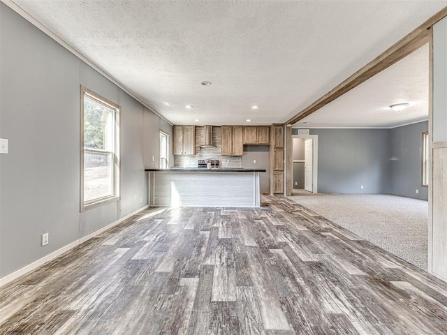 unfurnished living room with beamed ceiling, a textured ceiling, hardwood / wood-style flooring, and ornamental molding