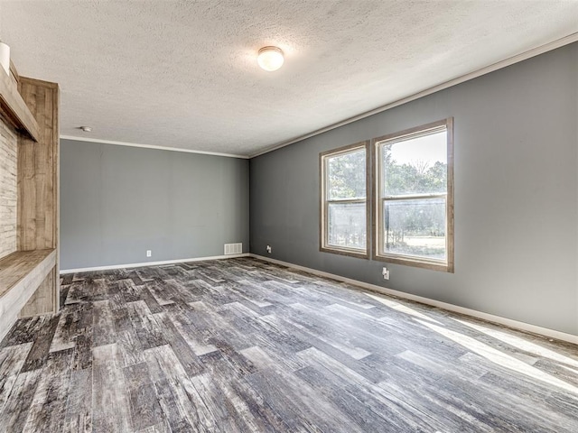 empty room featuring dark wood-type flooring, a textured ceiling, and ornamental molding