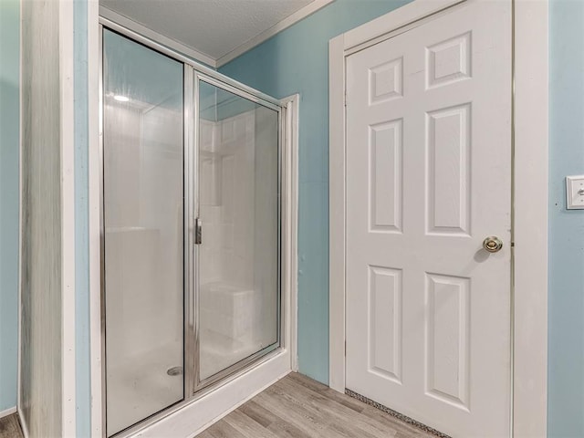 bathroom featuring a textured ceiling, hardwood / wood-style floors, and an enclosed shower