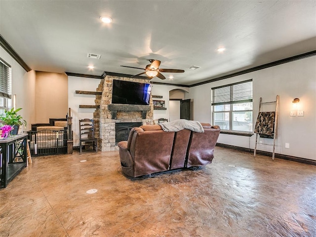 living room featuring ceiling fan, a stone fireplace, and crown molding