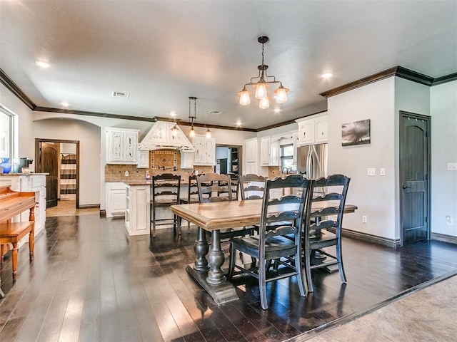 dining area featuring dark hardwood / wood-style floors, an inviting chandelier, and ornamental molding