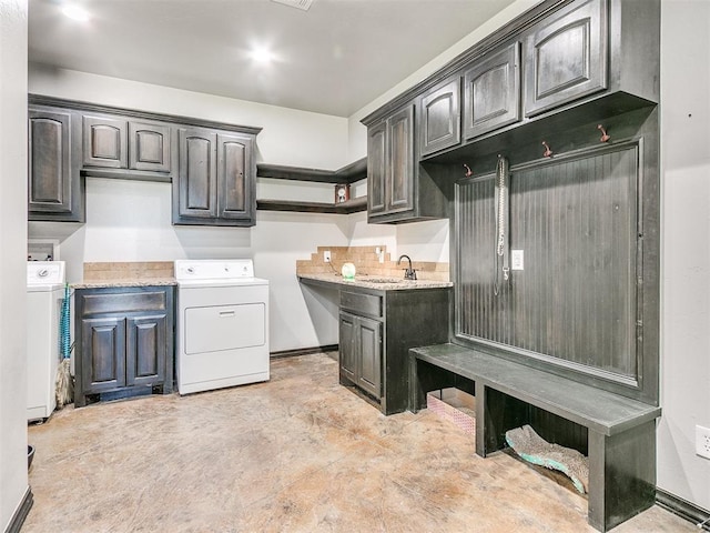 kitchen featuring washing machine and dryer, light stone countertops, and sink