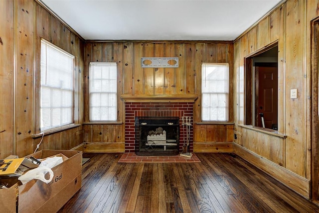 unfurnished living room featuring dark hardwood / wood-style floors, wood walls, and a fireplace