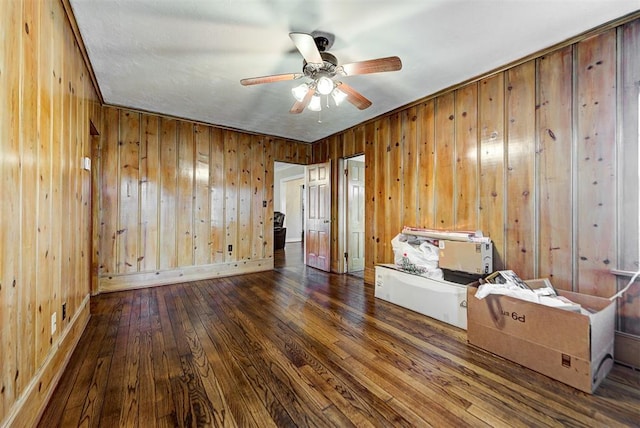 unfurnished room with wooden walls, dark hardwood / wood-style flooring, and ceiling fan