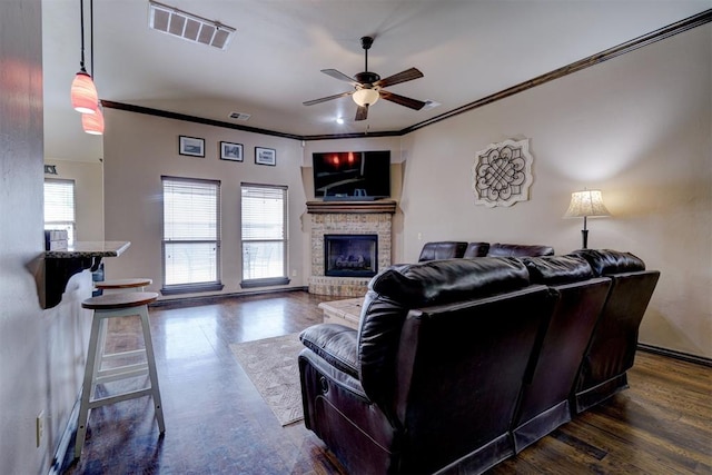 living room with a fireplace, dark hardwood / wood-style flooring, ceiling fan, and crown molding