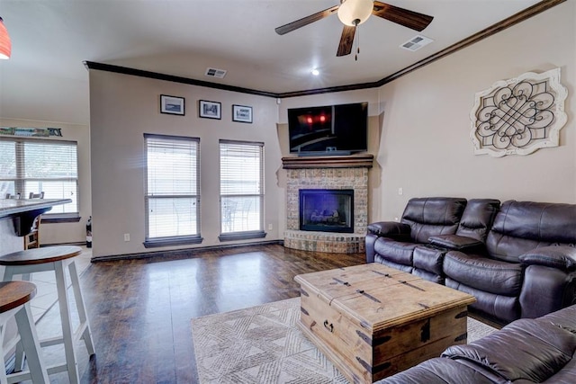 living room featuring a fireplace, dark wood-type flooring, ceiling fan, and ornamental molding