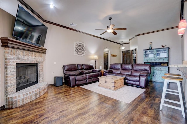 living room with a fireplace, crown molding, dark hardwood / wood-style flooring, and ceiling fan