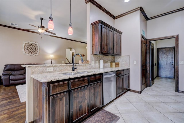 kitchen with light stone countertops, stainless steel dishwasher, dark brown cabinets, sink, and pendant lighting