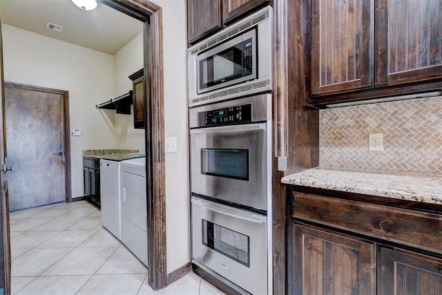 kitchen with light stone countertops, decorative backsplash, stainless steel appliances, washer and dryer, and light tile patterned flooring