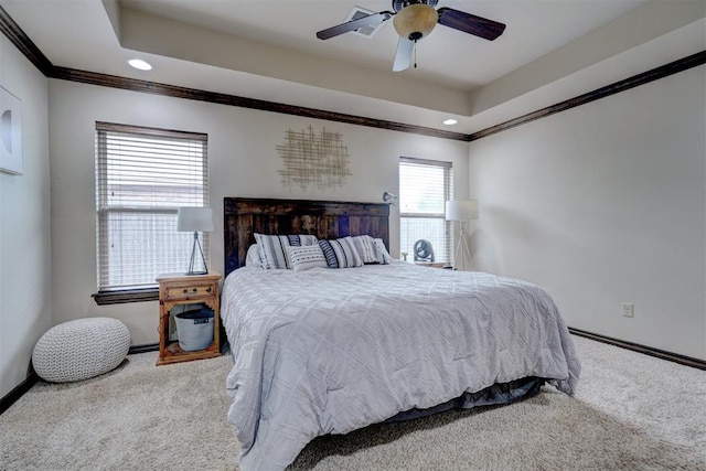 bedroom with ceiling fan, carpet floors, ornamental molding, and a tray ceiling