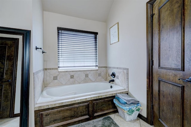 bathroom with tiled tub, tile patterned flooring, and lofted ceiling