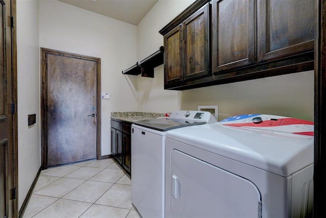 laundry area with washing machine and clothes dryer, light tile patterned flooring, and cabinets