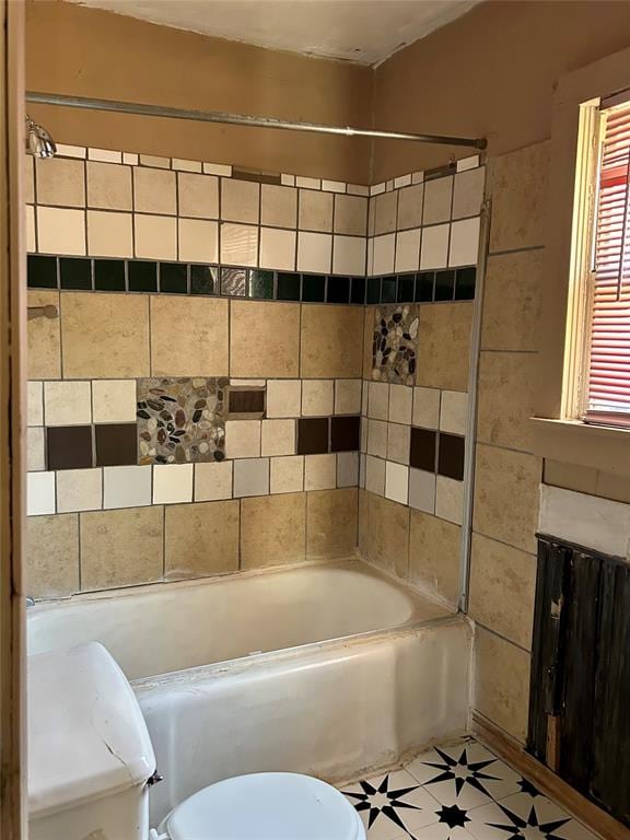 bathroom featuring tile patterned floors, tiled shower / bath combo, and toilet