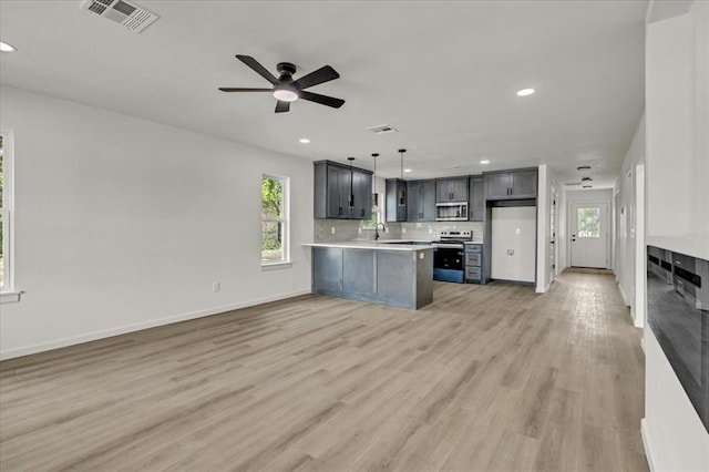 kitchen featuring sink, gray cabinets, light wood-type flooring, appliances with stainless steel finishes, and decorative light fixtures