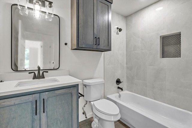 full bathroom featuring tile patterned floors, vanity, tiled shower / bath, and toilet