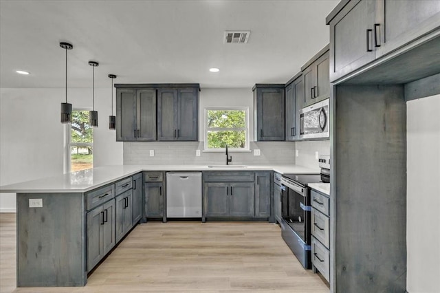 kitchen with sink, hanging light fixtures, kitchen peninsula, light hardwood / wood-style floors, and appliances with stainless steel finishes