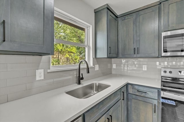 kitchen featuring gray cabinetry, decorative backsplash, sink, and stainless steel appliances