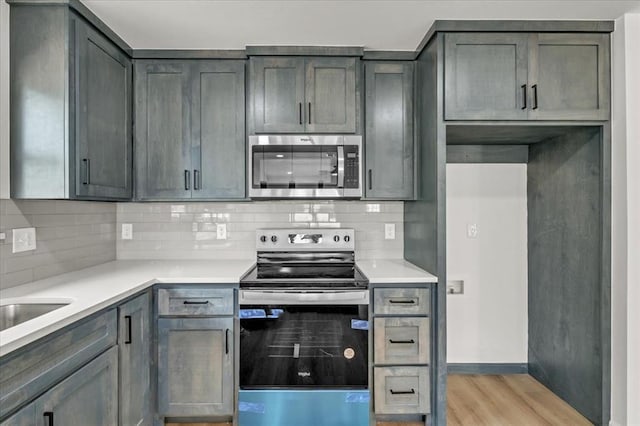 kitchen with decorative backsplash, stainless steel appliances, and light hardwood / wood-style floors