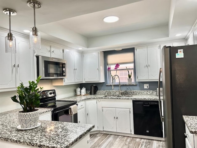 kitchen featuring white cabinetry, sink, light stone counters, black appliances, and a raised ceiling