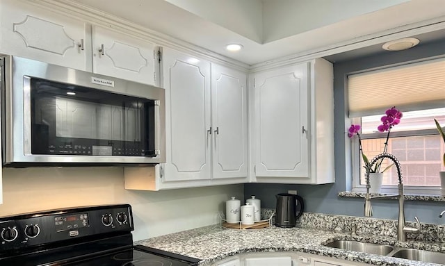 kitchen with sink, black electric range, and white cabinets