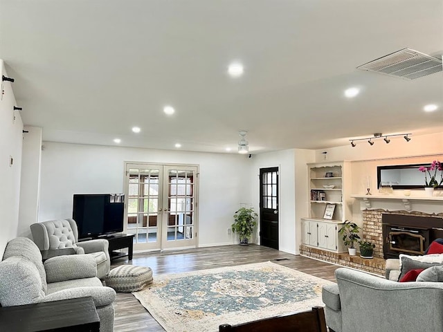 living room with french doors, wood-type flooring, and a brick fireplace