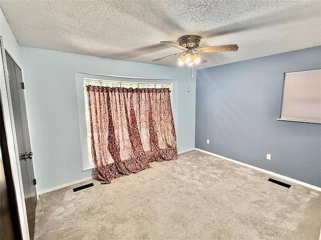 empty room featuring ceiling fan, light carpet, and a textured ceiling