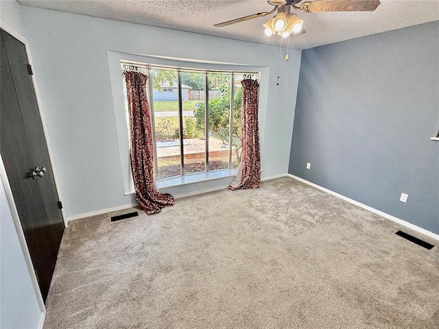 spare room featuring ceiling fan, carpet, and a textured ceiling