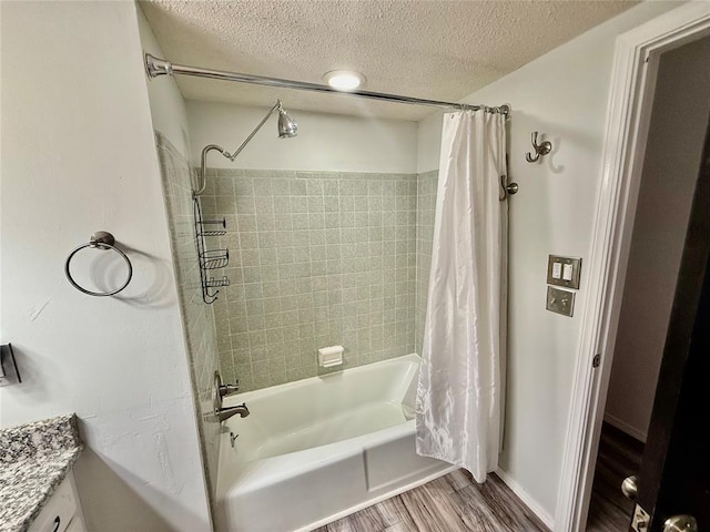 bathroom with hardwood / wood-style flooring, vanity, shower / bathtub combination with curtain, and a textured ceiling