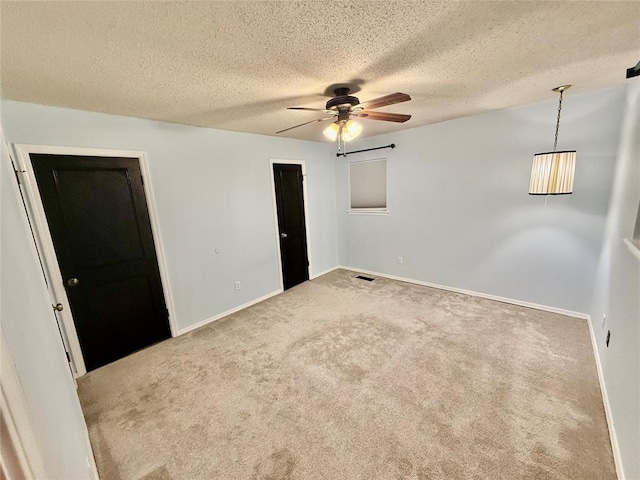 carpeted empty room with ceiling fan and a textured ceiling