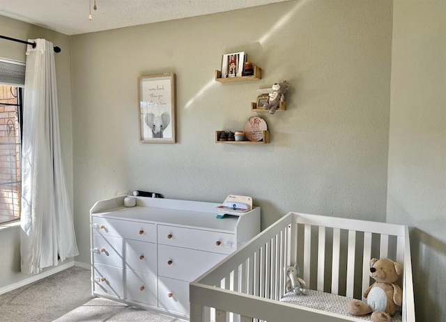 carpeted bedroom featuring a nursery area