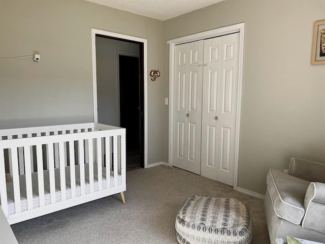 carpeted bedroom with a textured ceiling, a closet, and a nursery area