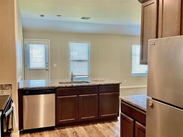 kitchen featuring light stone countertops, sink, light hardwood / wood-style floors, and appliances with stainless steel finishes