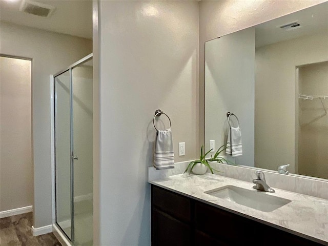 bathroom featuring vanity, hardwood / wood-style flooring, and a shower with door