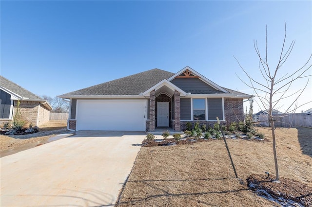 view of front of property with driveway, a garage, a shingled roof, fence, and brick siding