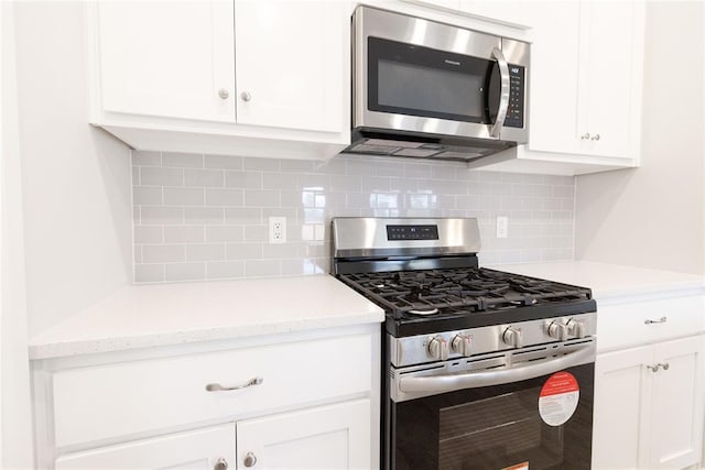 kitchen featuring tasteful backsplash, white cabinets, and stainless steel appliances