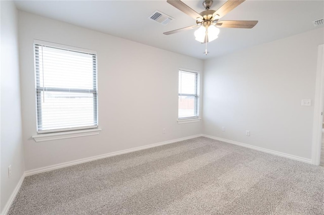 carpeted empty room with visible vents, baseboards, and a ceiling fan