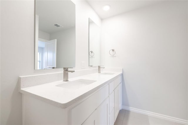 bathroom featuring a sink, visible vents, double vanity, and tile patterned flooring