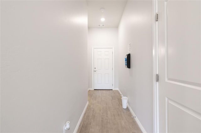 corridor with light wood-style flooring, baseboards, and visible vents