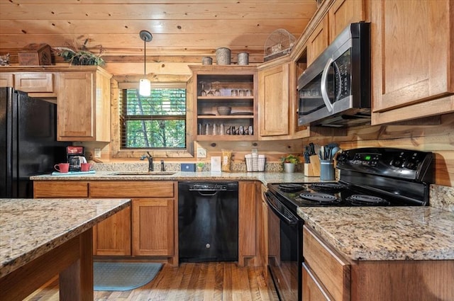 kitchen with black appliances, sink, decorative light fixtures, light hardwood / wood-style floors, and light stone counters