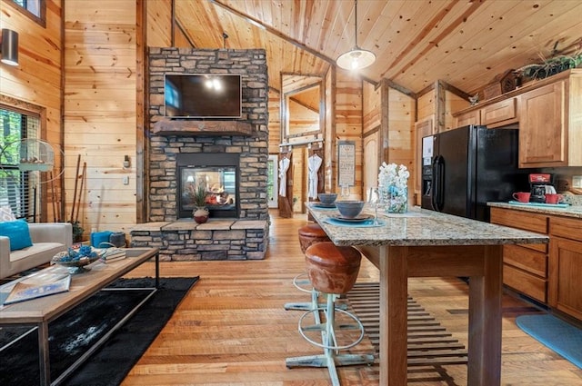 kitchen featuring light hardwood / wood-style flooring, black fridge, wooden walls, and wood ceiling