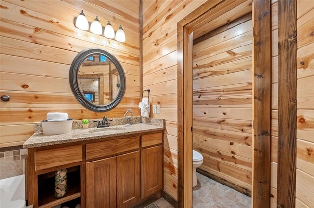 bathroom featuring vanity, toilet, and wooden walls